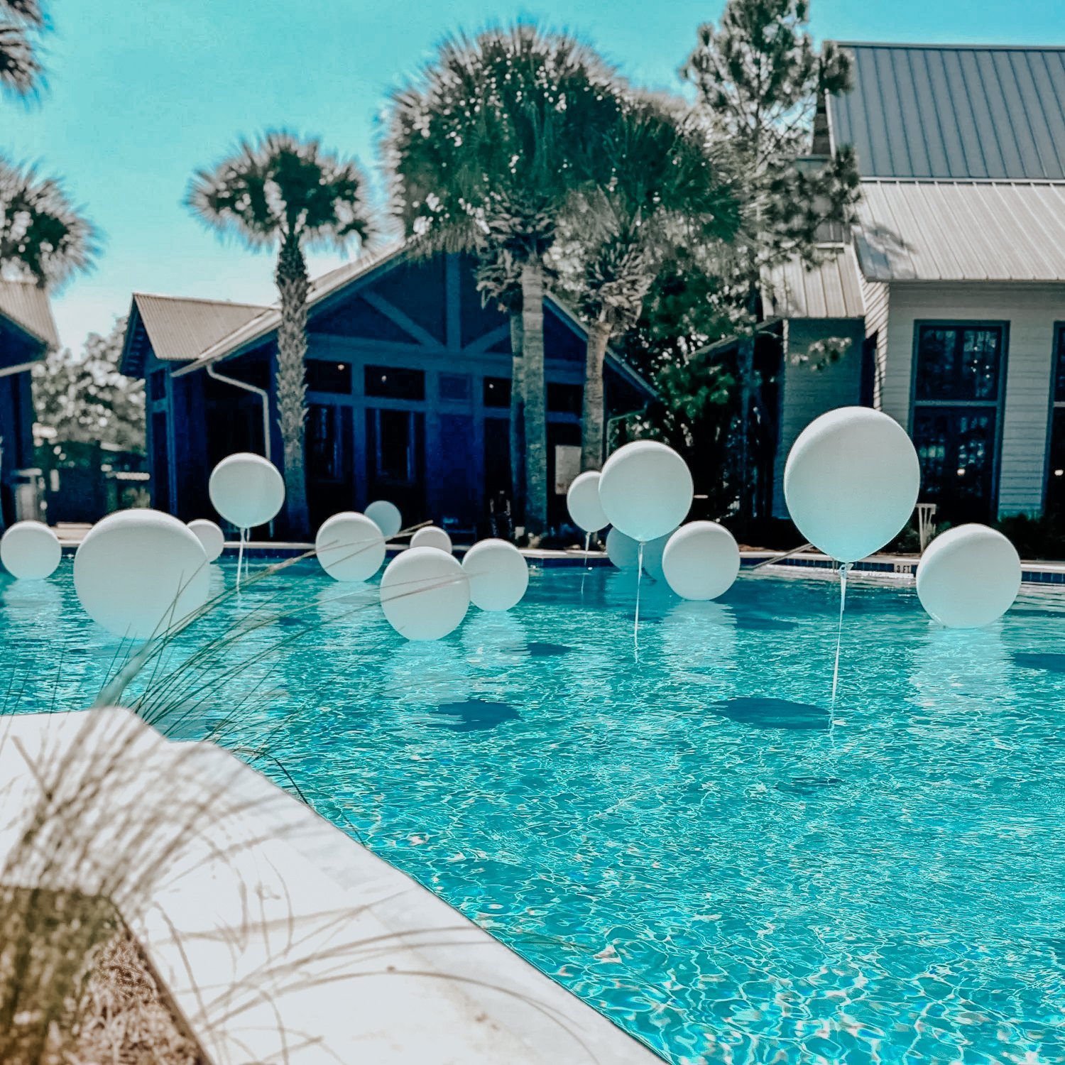 White pool balloons floating on a blue swimming pool for a 30A outdoor celebration.