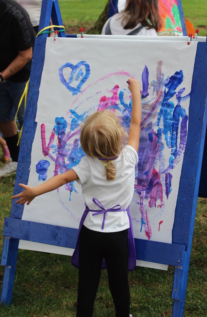 Kid painting with their hands at Art in the Park Event.