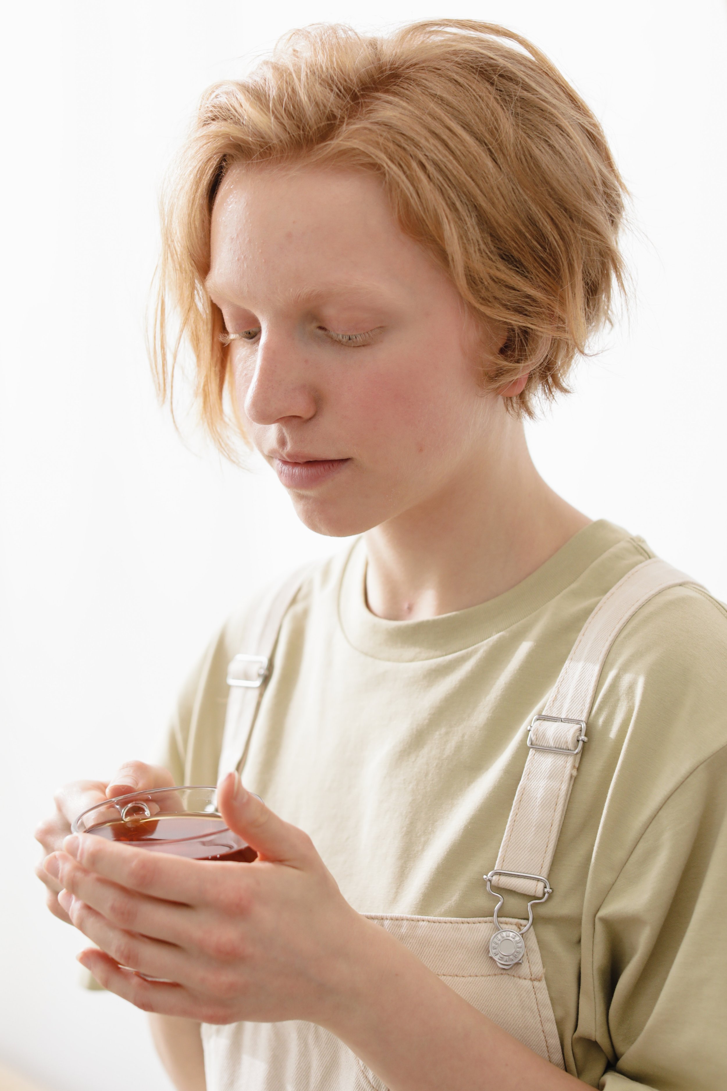 A young woman stares down at a cup of tea in her hands