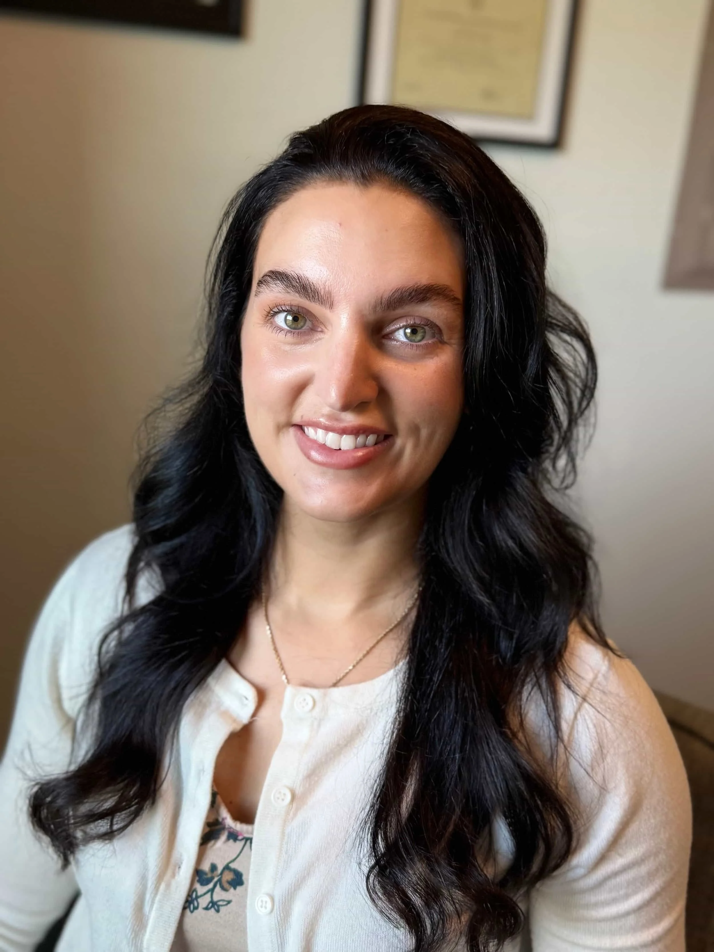 ATX Mental Health therapist Amanda smiles at the camera with long dark hair wearing a white sweater