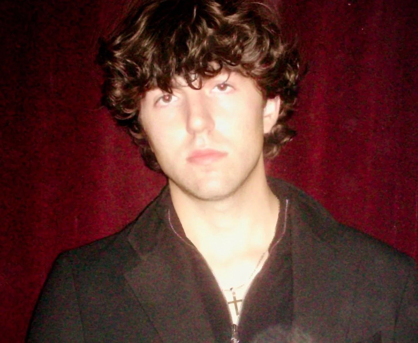 George Pareti, Chicago artist and founder of ForTheYouth, photographed in front of a red curtain.