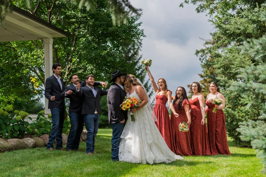 Wedding party at Country Coach House, Burlington, IL, with groomsmen in jeans and boots, bridesmaids in burnt orange dresses, and the bride in lace with fall bouquets.