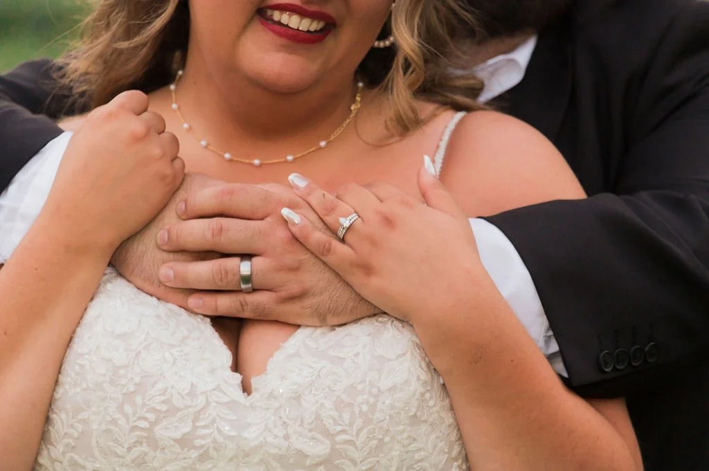 An emrace showing the bride and groom's weddig rings, from  Nelson's Jewlery in Crystal Lake, IL. Photo by James A Vitullo at Country Coach House, Burlington, IL.