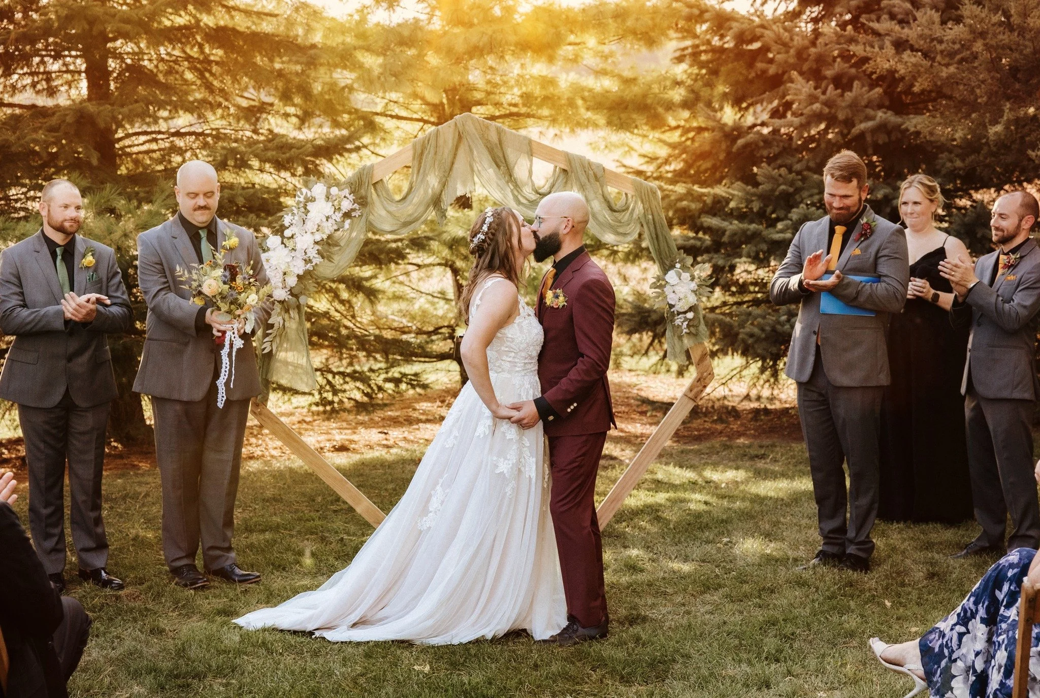 First kiss beneath the heptagon arbor during an outdoor wedding ceremony at Country Coach House in Burlington, IL.
