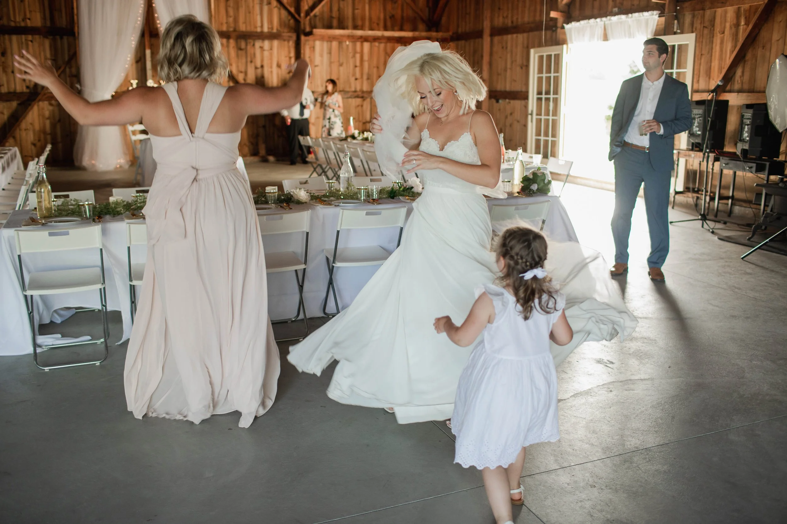 Bride dancing and laughing with a flower girl during a wedding at Country Coach House in Burlington, IL.