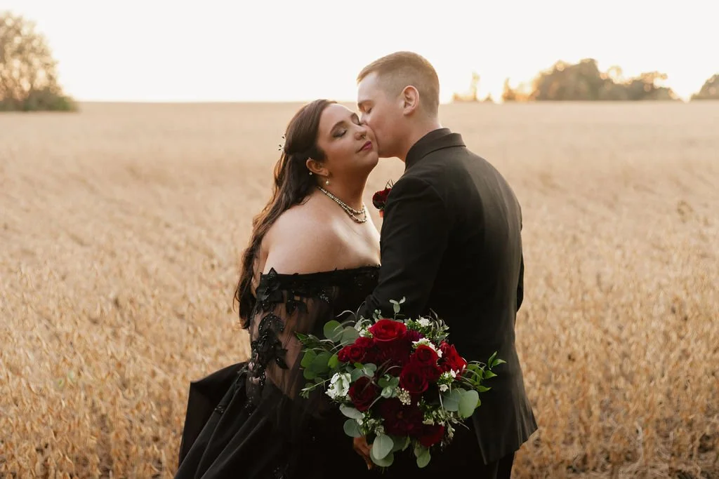 The groom gently kisses his bride’s cheek in front of a golden farm field at Country Coach House, a rustic wedding venue in Burlington, Illinois.