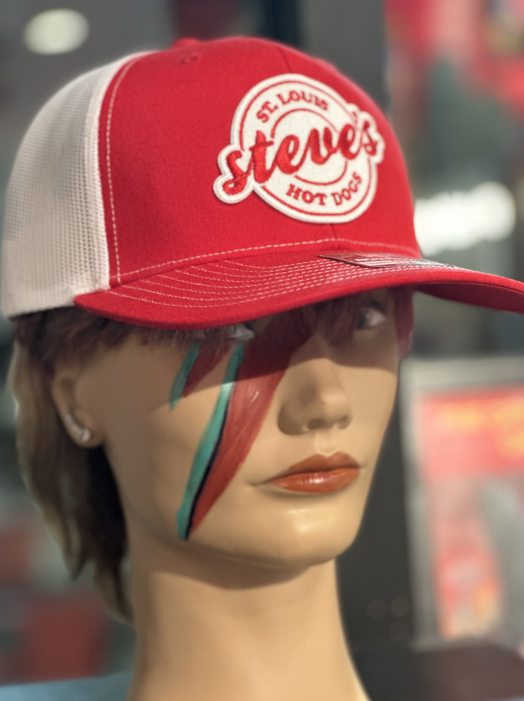 A red and white hat with a red and white patch with the Steve's Hot Dogs logo.