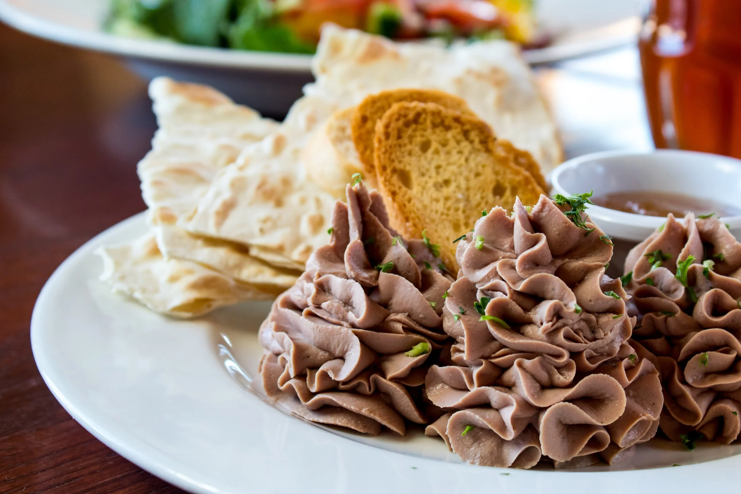 Plate with pate swirls, bread slices, flatbread, and small dish of sauce
