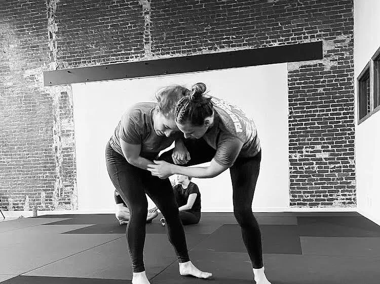 female grappler performing single leg takedown during women's bjj class