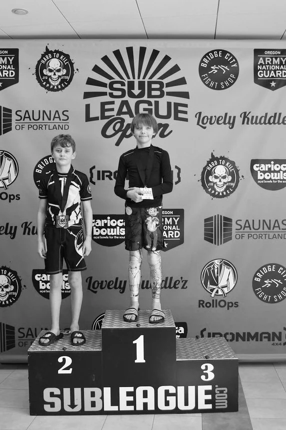 Kids' BJJ team member atop podium after placing first in his no gi bracket the 2026 Sub League Open