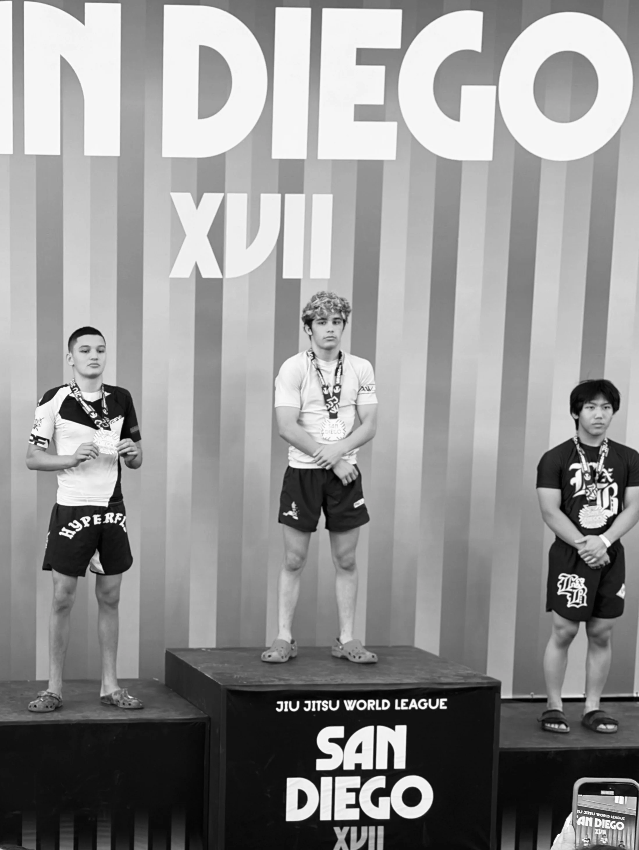 OGA competitor in first place on podium after winning his juvenile green/blue belt division at Jiu Jitsu World League in San Diego