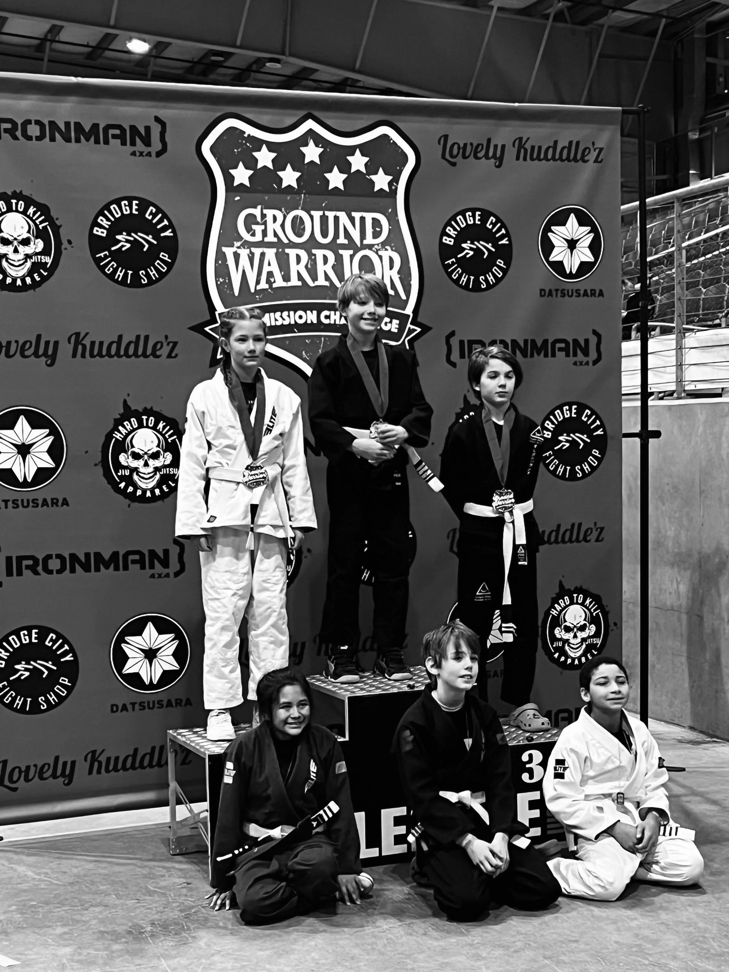 Oregon Grappling Arts kids' Brazilian Jiu jitsu team competitor standing atop podium with gold medal at Ground Warrior tournament