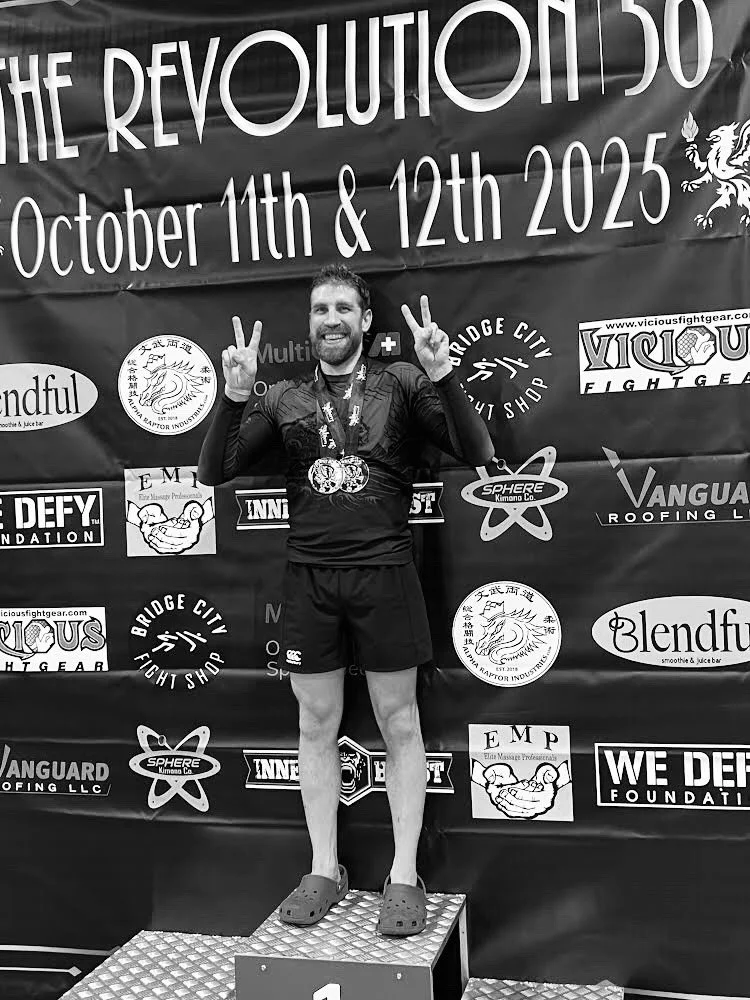 Oregon Grappling Arts adult BJJ competitor standing atop podium after winning Revolution 56 grappling tournament