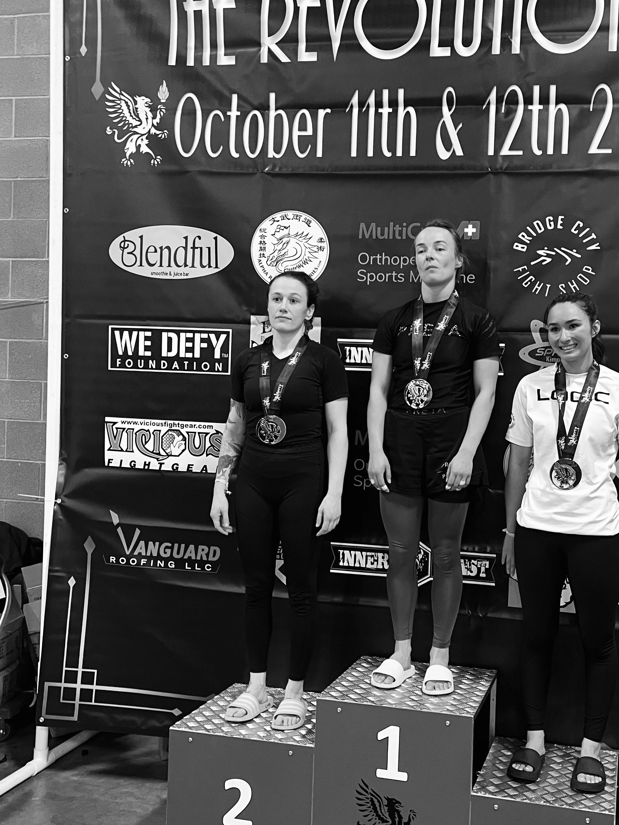 OGA womens jiu jitsu team member standing on podium after placing second at the Revolution 56 BJJ tournament