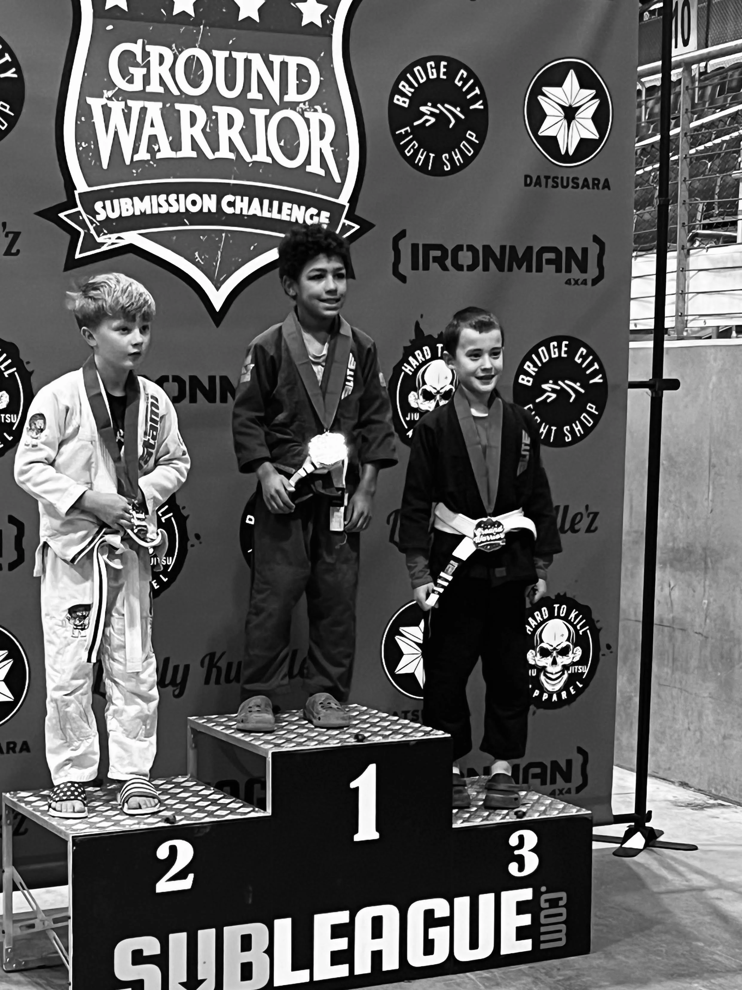 Kids jiu jitsu team competitor standing on podium after placing third at Ground Warrior tournament