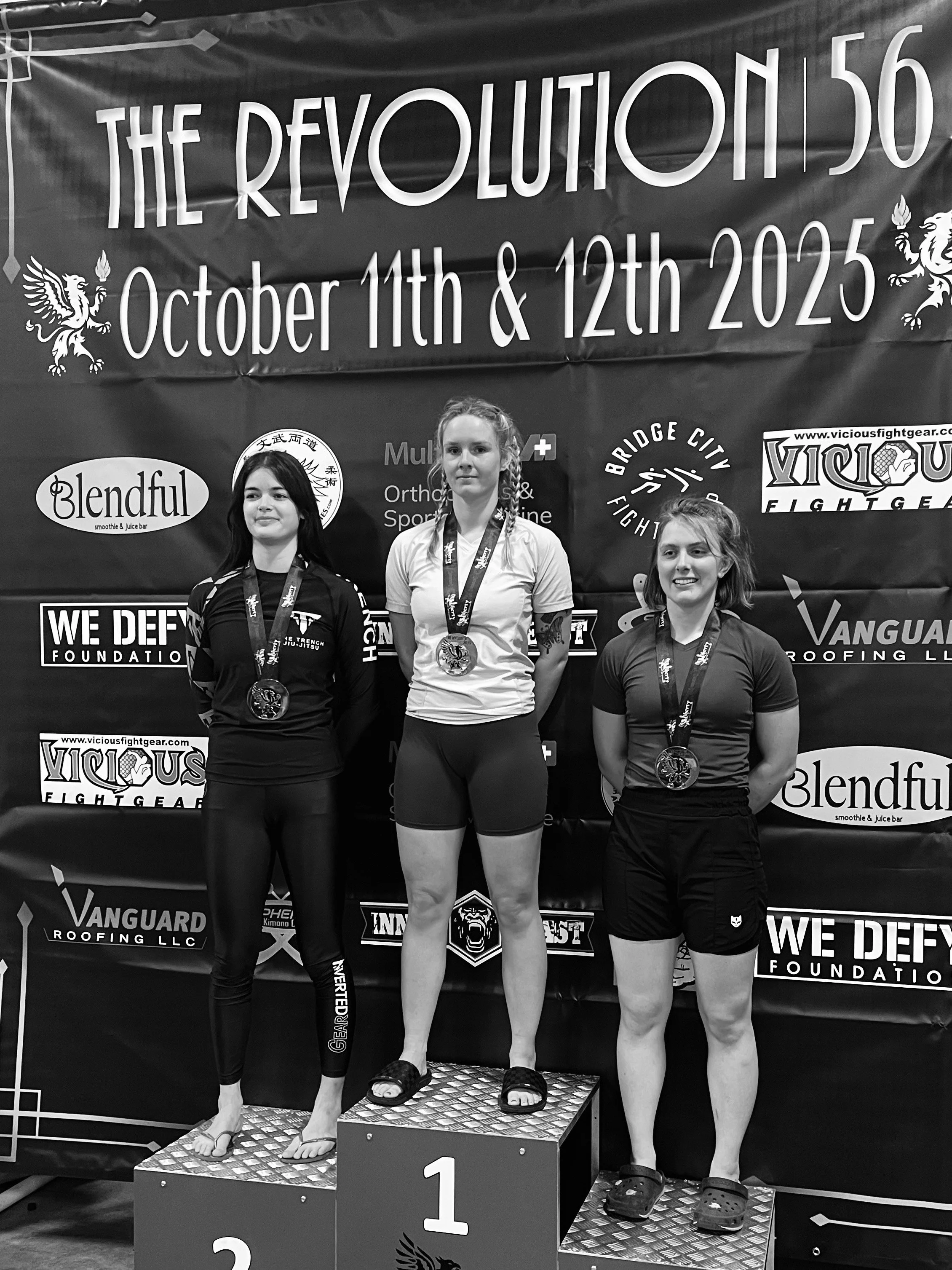 Women's BJJ team competitor with gold medal on podium after winning her bracket at the Revolution 56 grappling tournament in Seattle