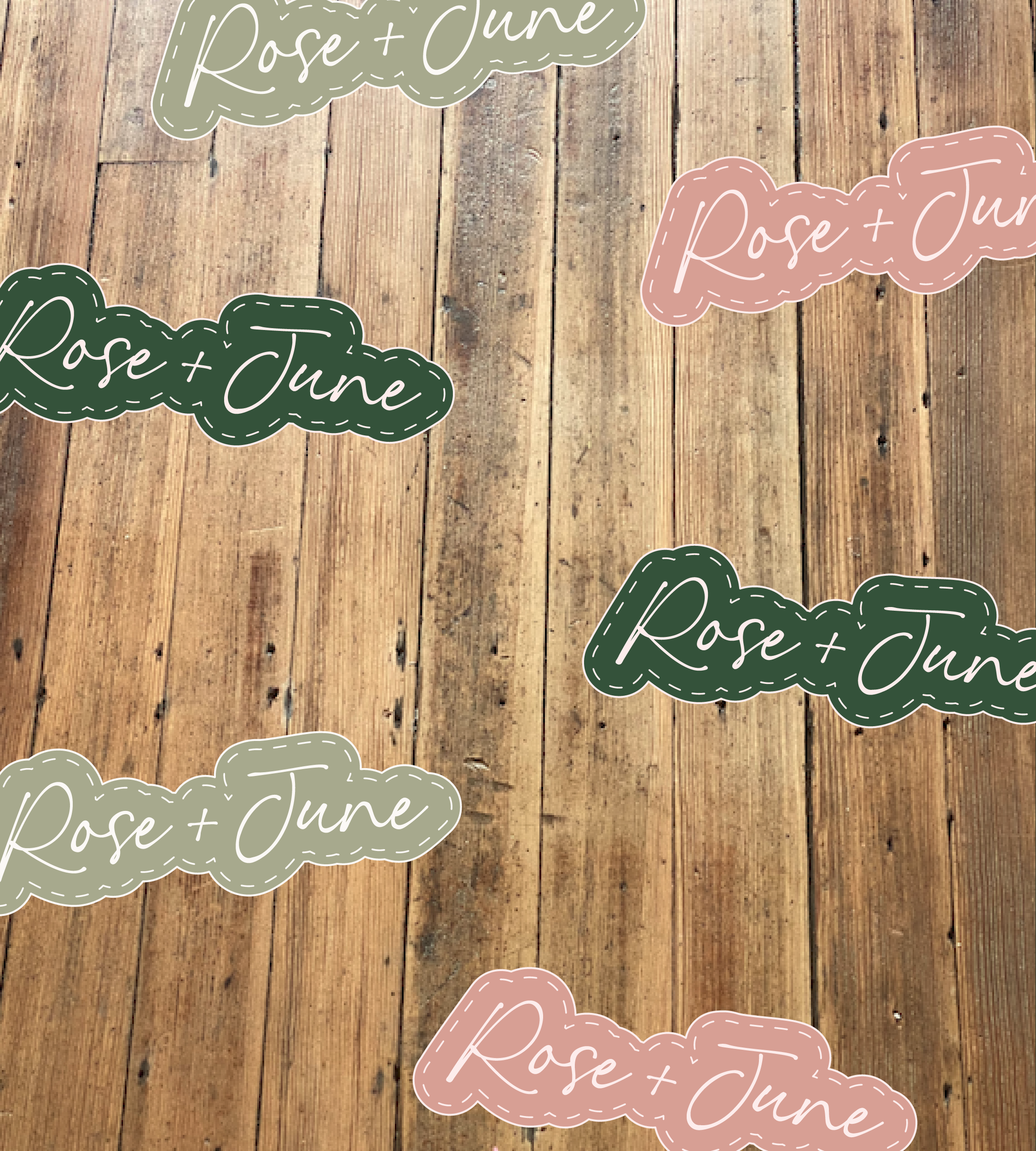 Several stickers on a wooden background with the text 'Rose + June' in various pastel colors including pink, green, and white.