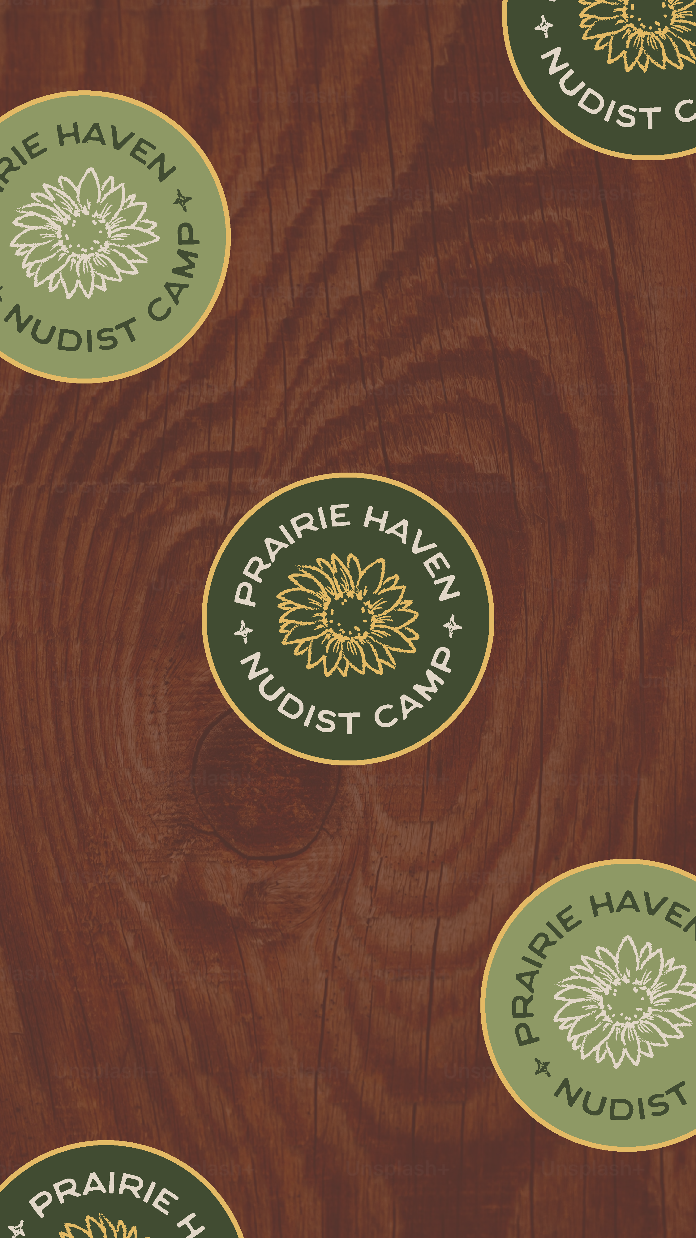 Stickers with the text "Prairie Haven Nudist Camp" and a sunflower logo on a wooden surface