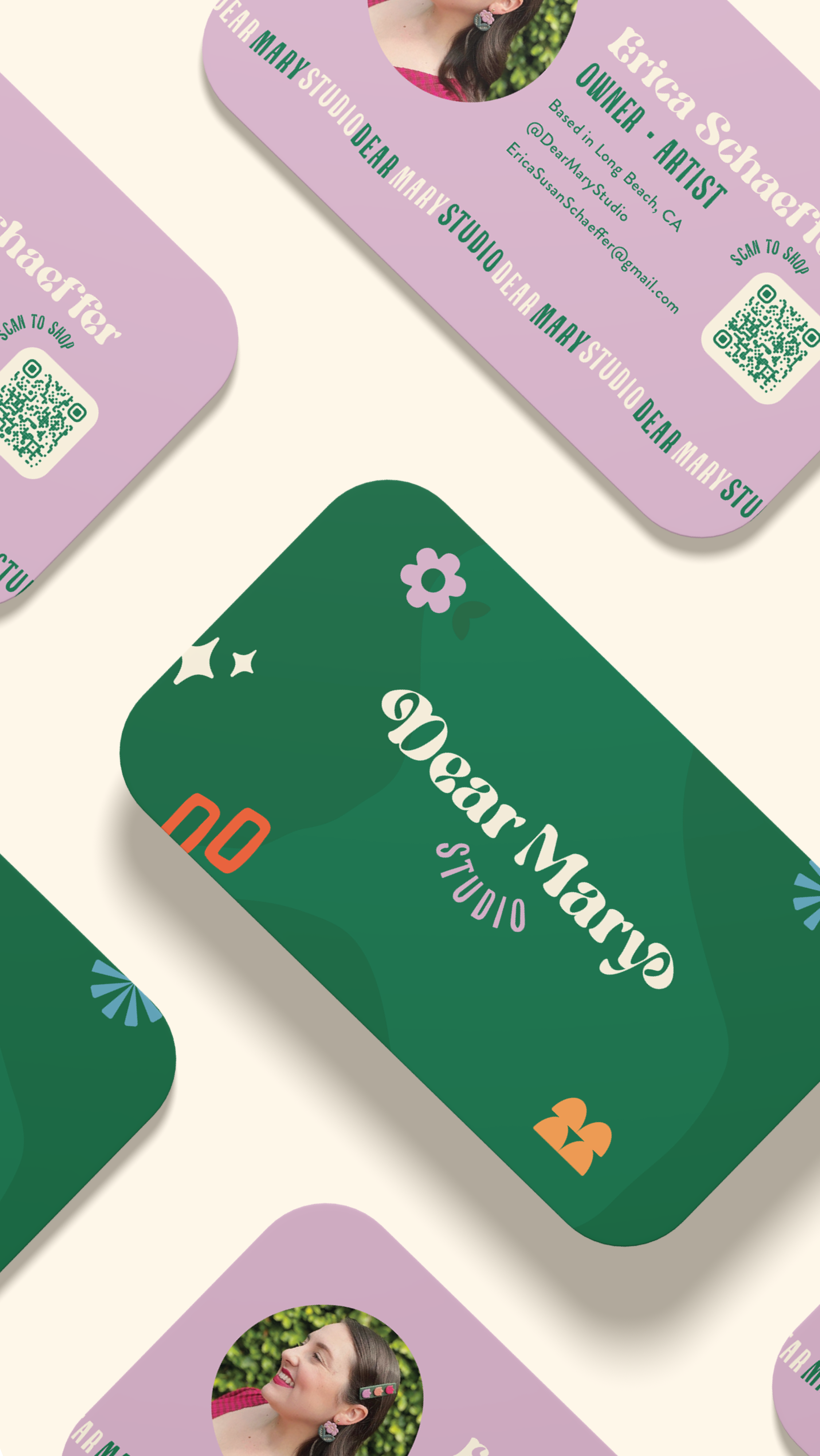 Business cards for Dear Mary Studio with one card displaying a green background, floral design, and studio name in white and purple text, and other cards in purple background with photo of a woman and contact details.