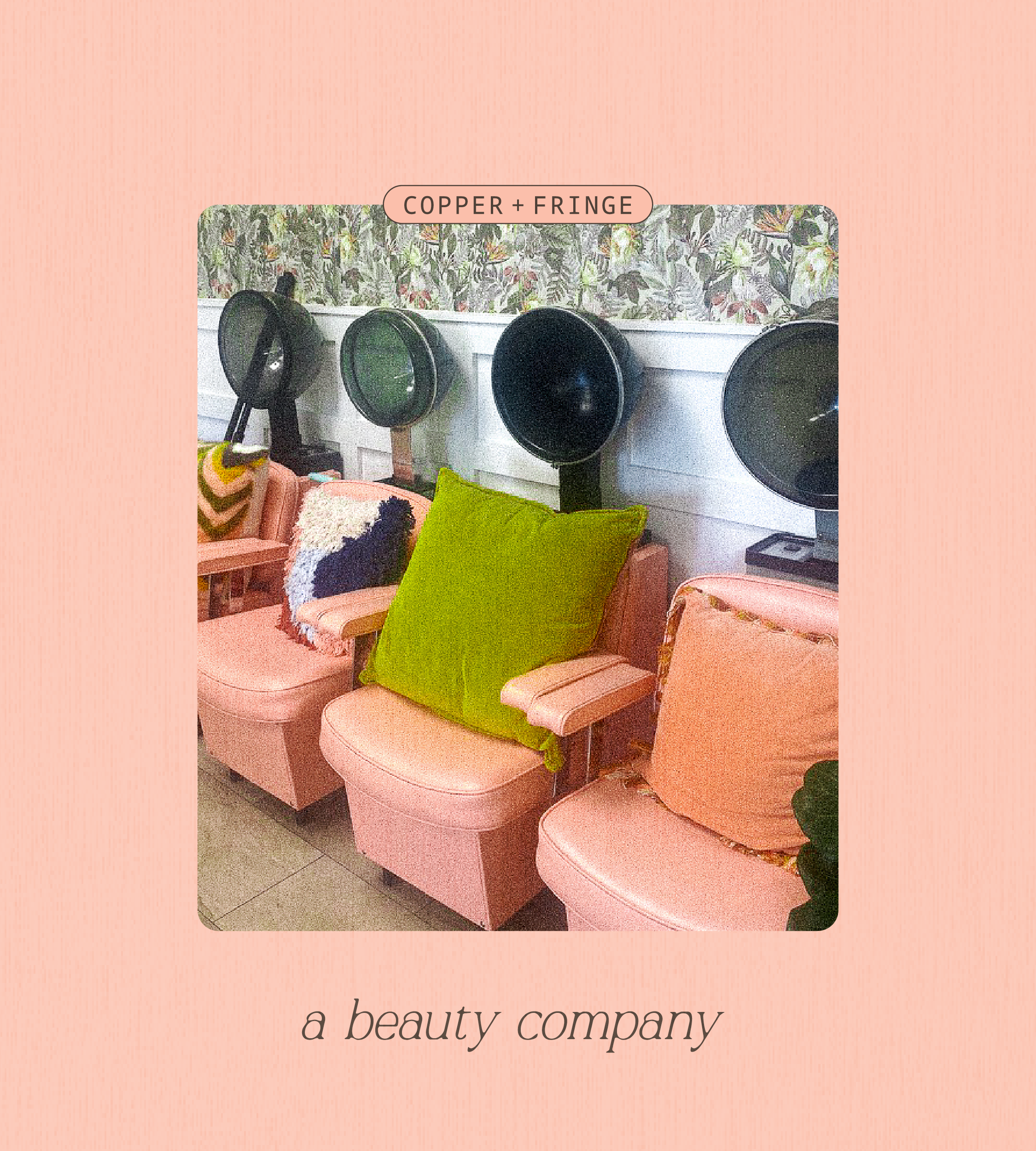 Pink chairs with green and patterned cushions in front of hair drying stations with black hoods, set against a floral wallpaper.