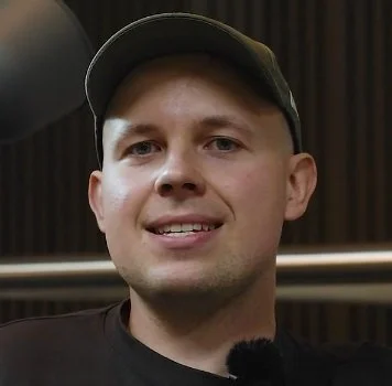 A person wearing a cap, smiling indoors.