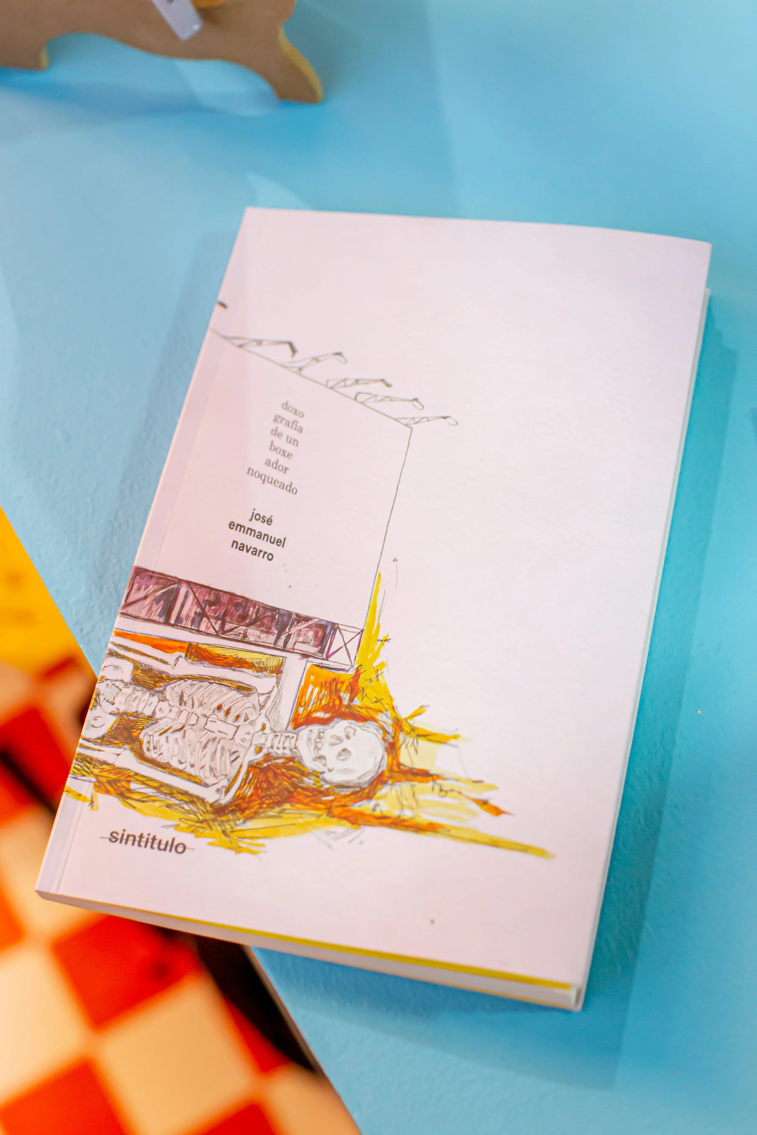 Fotografía de cubierta frente del libro "doxografía" con mesa azul de fondo durante presentación FIL GDL 2025. Fotografía © Luis Linares