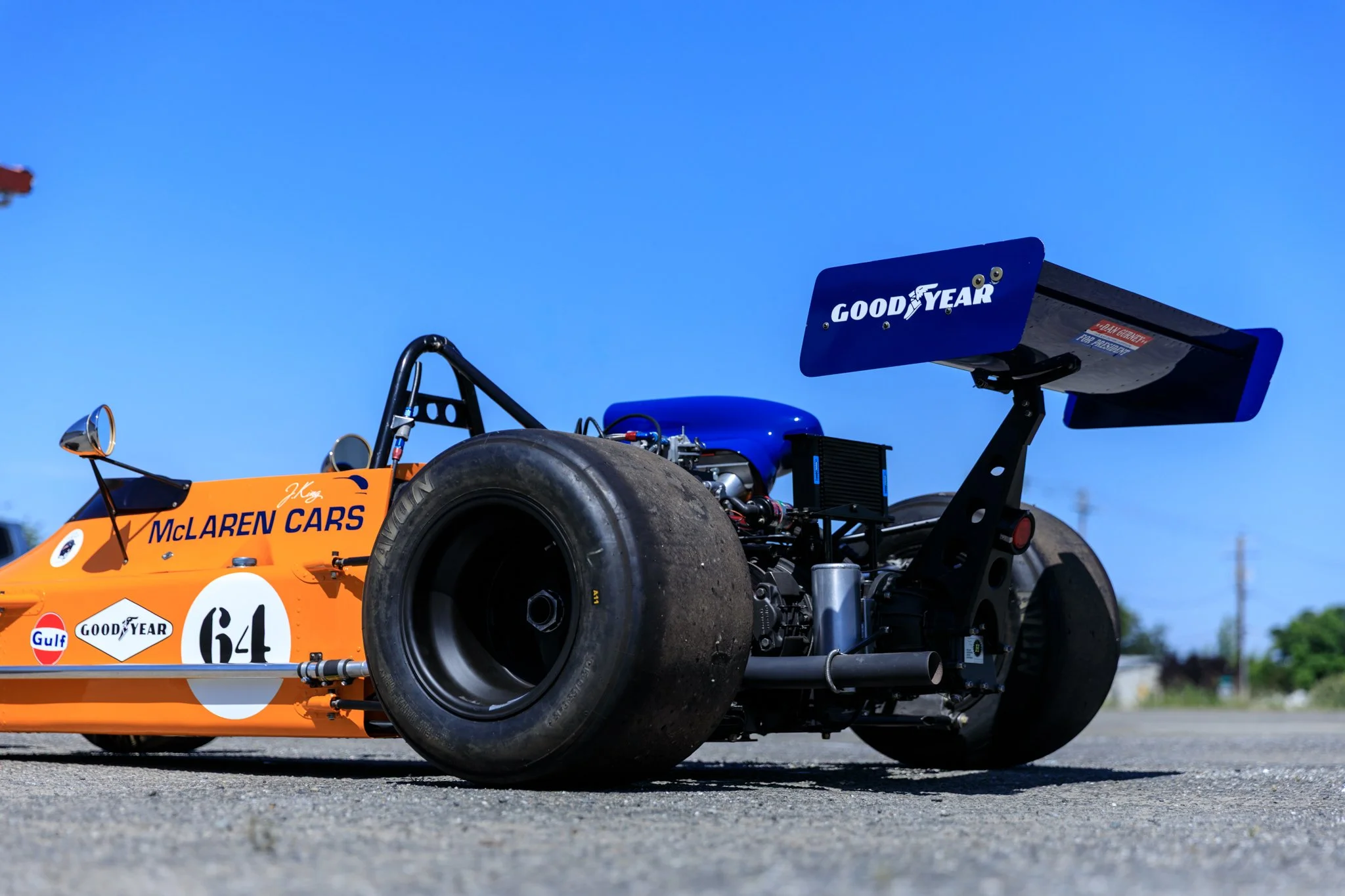 McLaren M21 Formula 2, chassis M21-3 — rear three-quarter right side view, race number 64, Goodyear rear tyre, Papaya Orange bodywork, blue rear wing