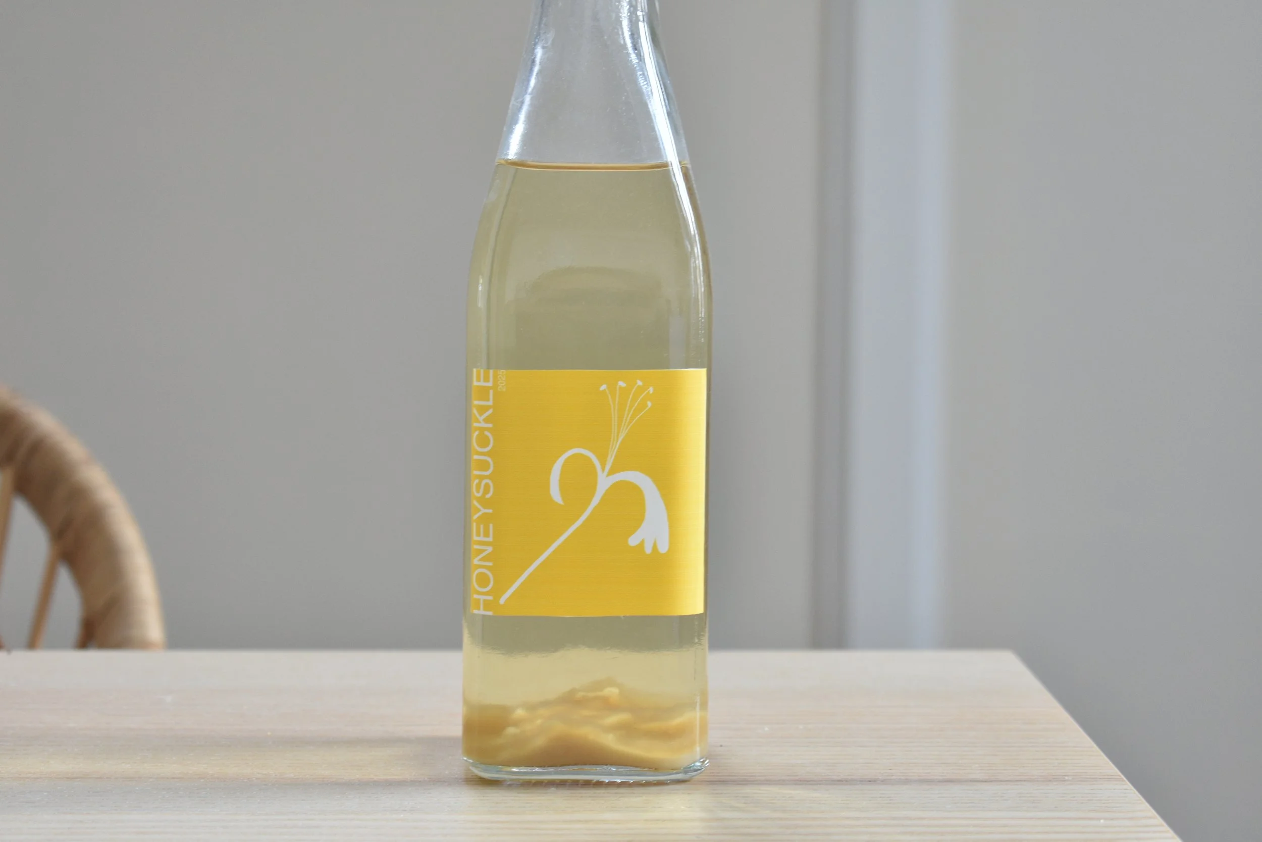 A glass bottle with honeysuckle liqueur with a yellow label