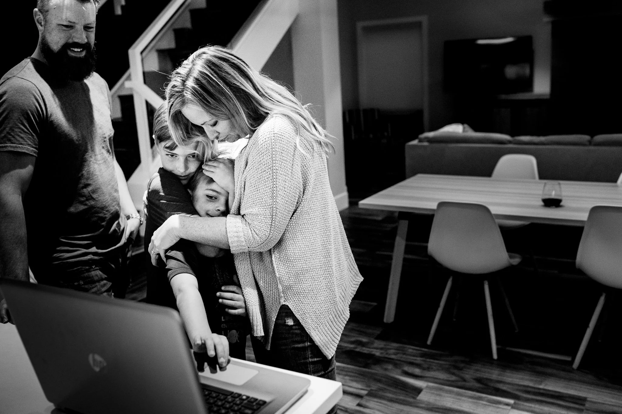 mother holding her boys as they look at the laptop