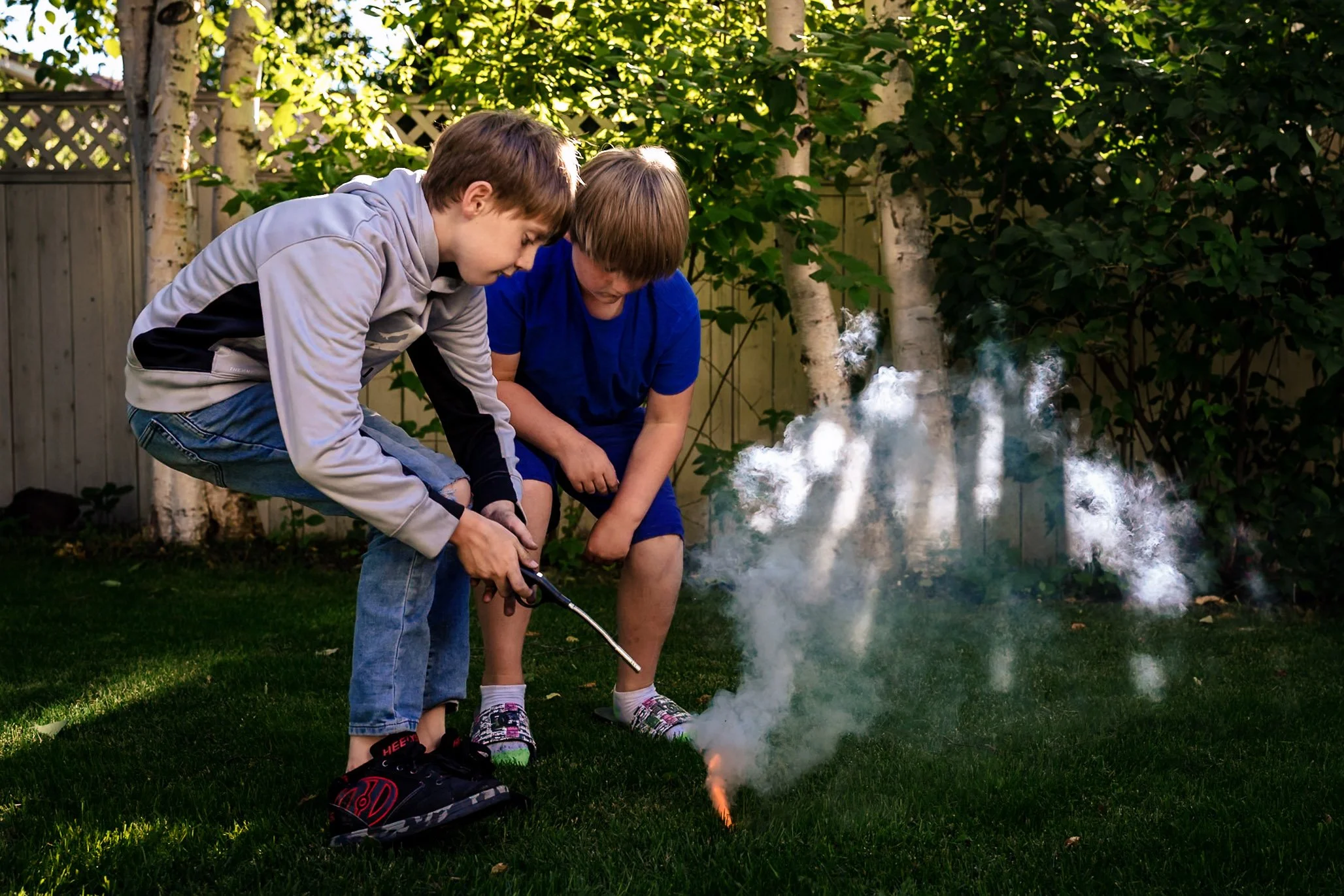 tween brothers lighting a smoke bomb in their backyard