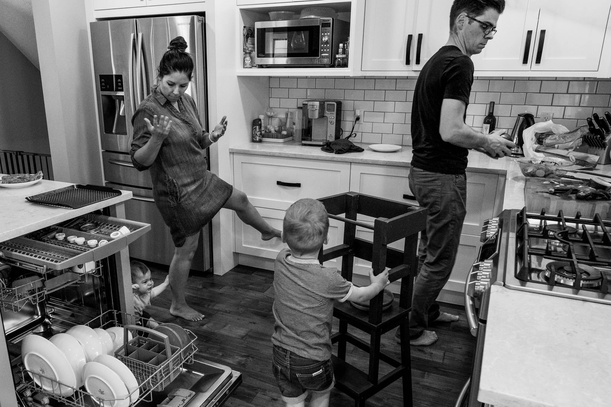 Mom and dad making dinner with their young children in the kitchen