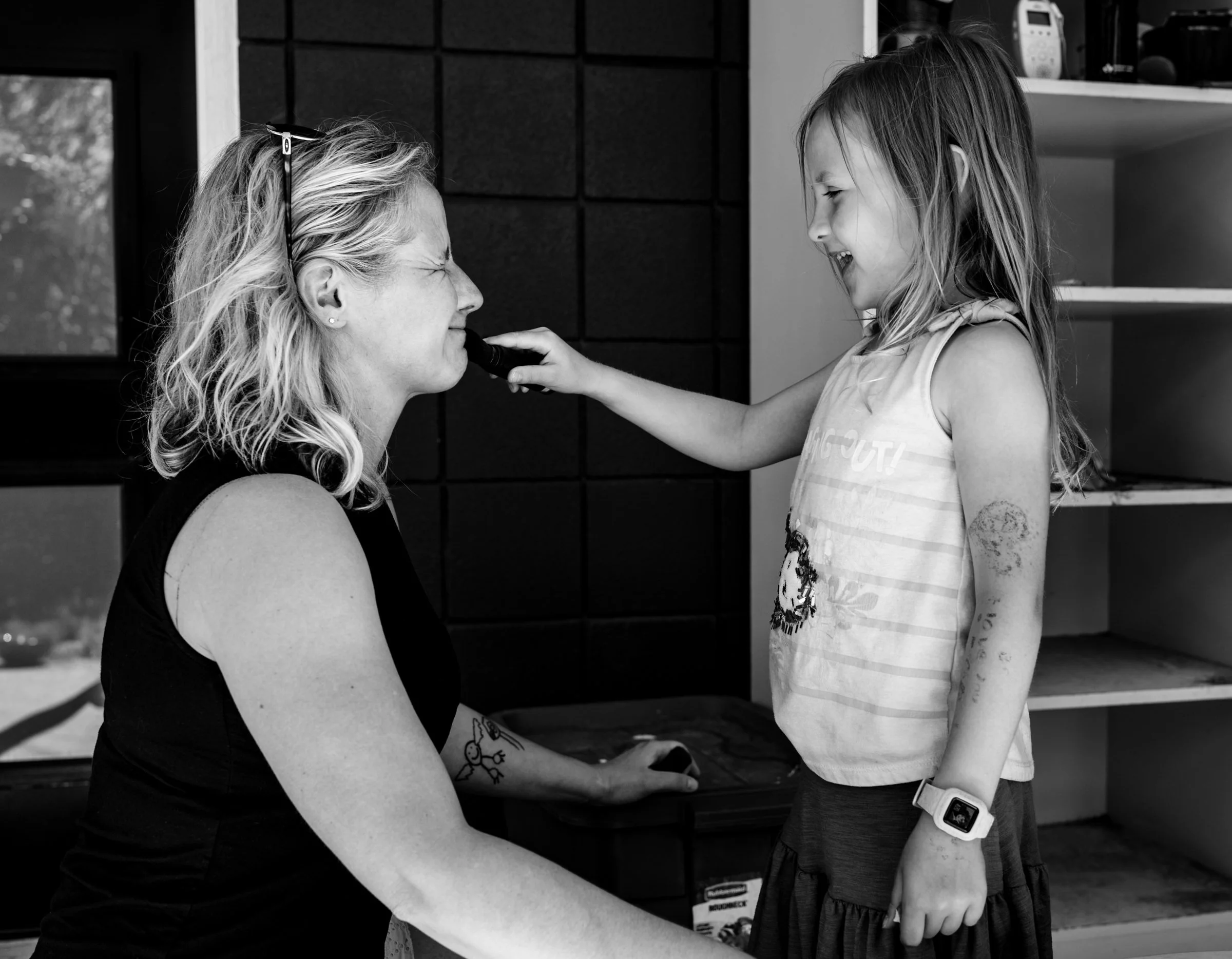 Young daughter roughly applying sunscreen to her mom's face during a Calgary family photography session