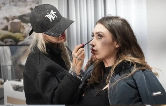 Makeup artist applying makeup to woman in a salon.