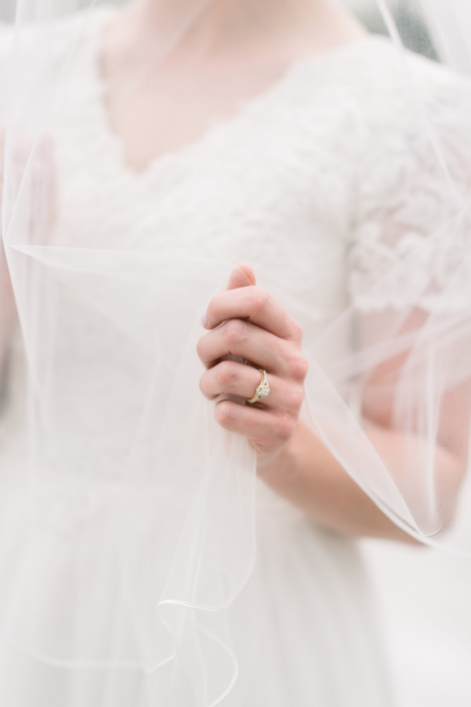  a bride in a wedding dress holding her vail and wearing a custom engagement ring 
