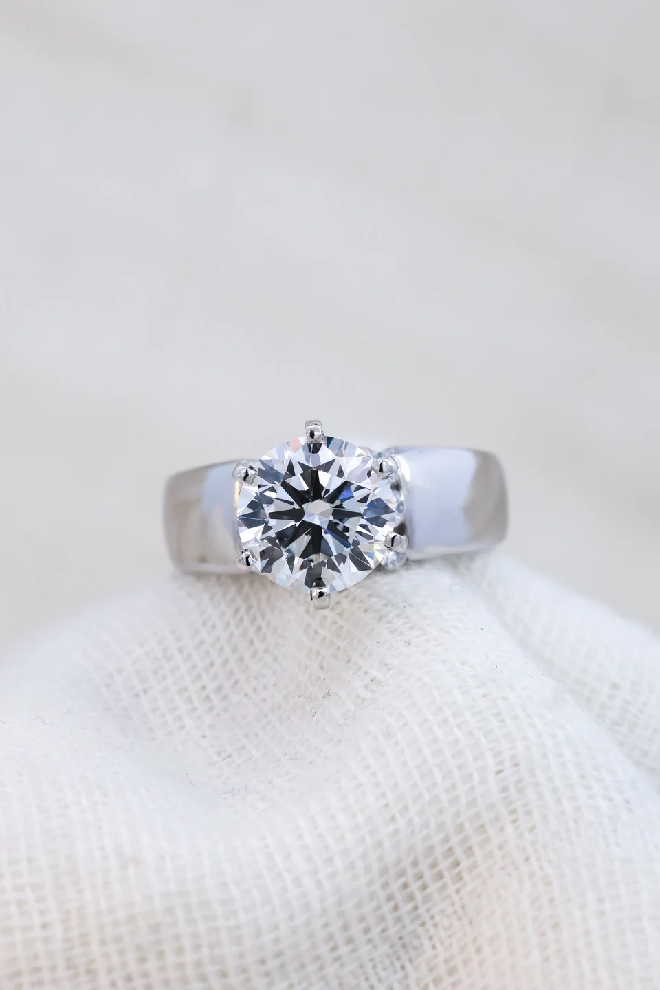 White gold engagement ring with thick band and channel set side diamonds, round center stone