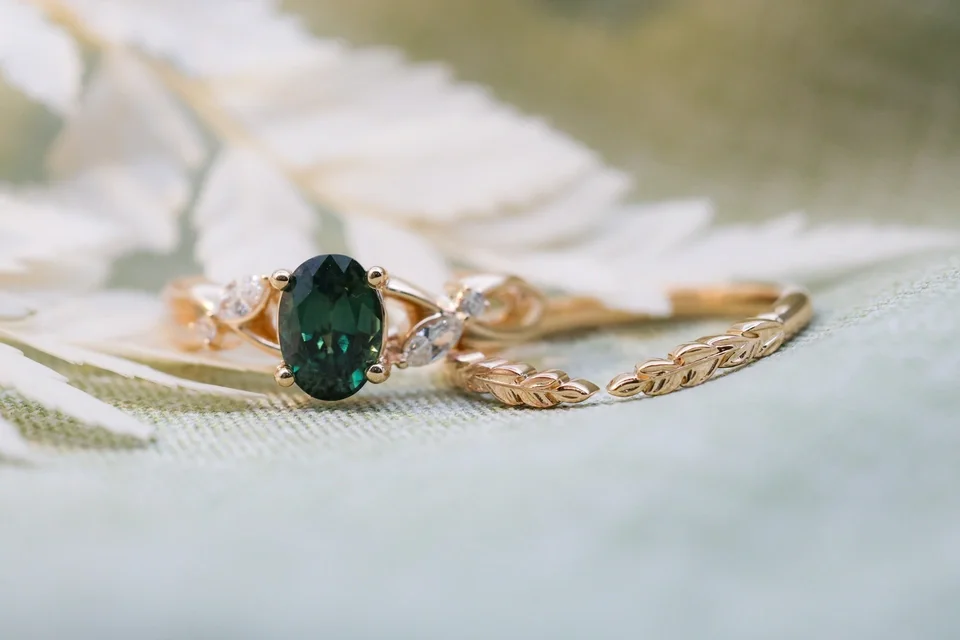 Custom yellow gold twist band ring with oval emerald center stone and marquise diamond side stones organic natural fairytale ring with matching leaf laurel yellow gold band