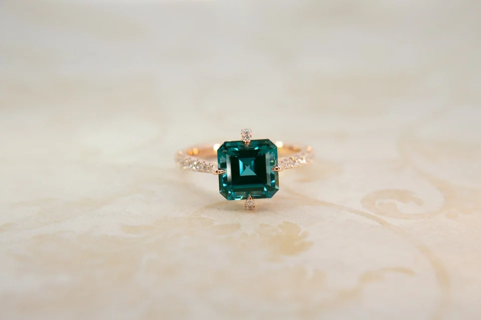 Custom yellow gold compass set ring with asscher cut square cut emerald center stone and pavé band