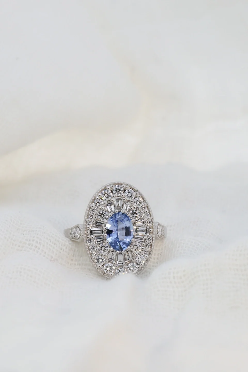 Platinum gothic vintage ring with diamond halo, milgrain, and a blue sapphire oval center stone
