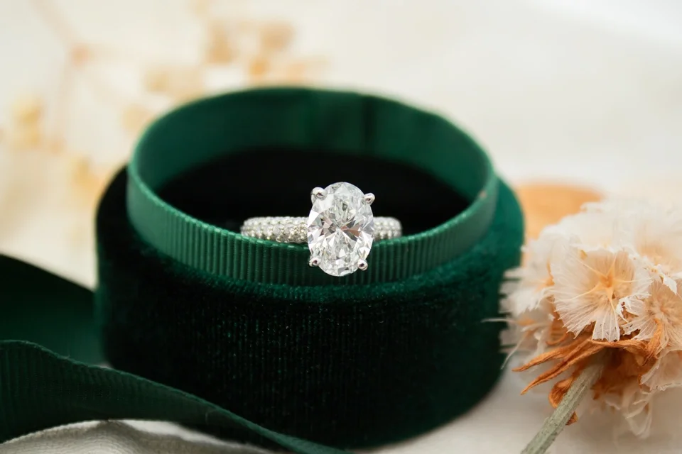 Platinum pavé style ring with oval diamond center stone in green box