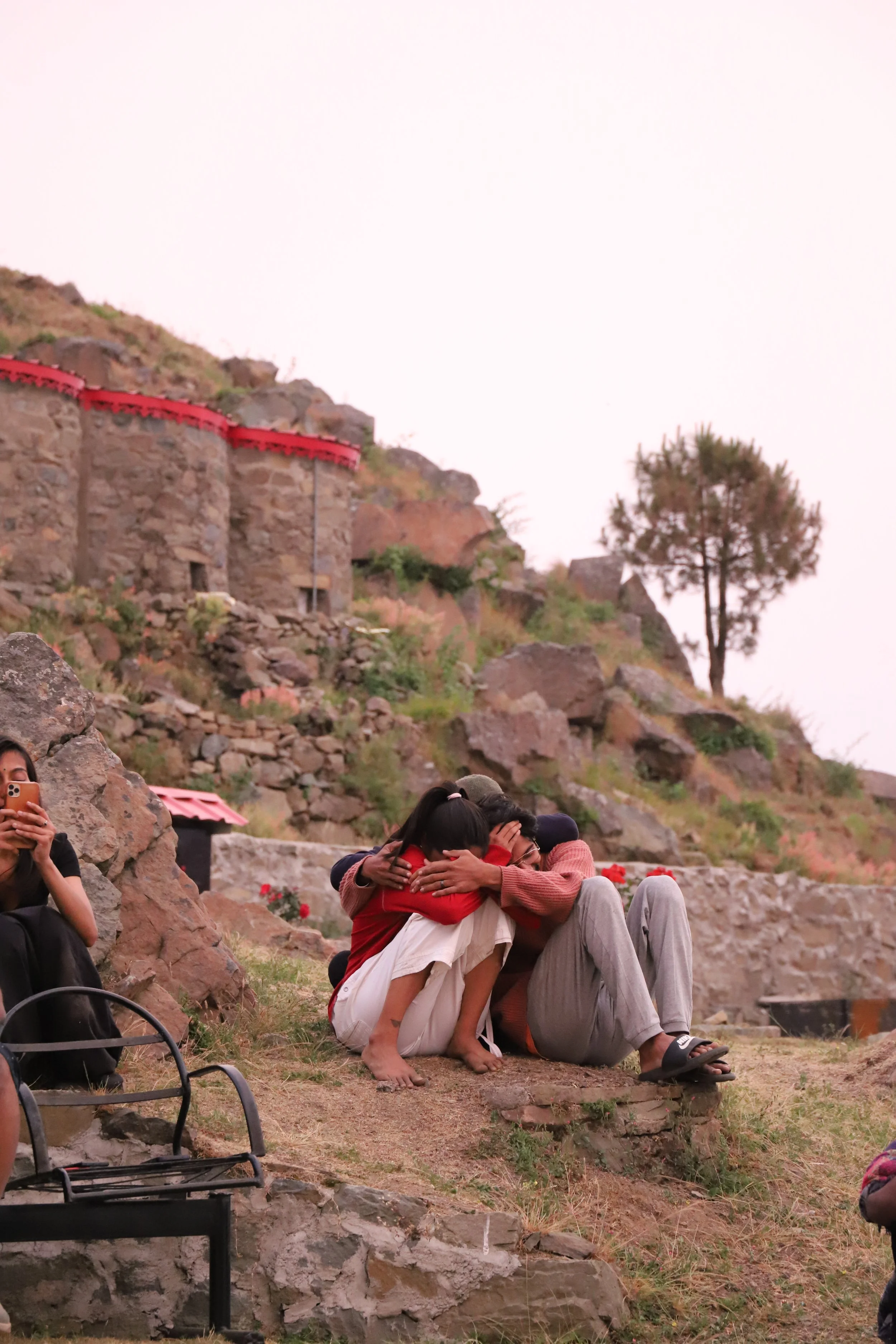 Two participants sitting quietly on a rocky hillside at a Yukah programme.