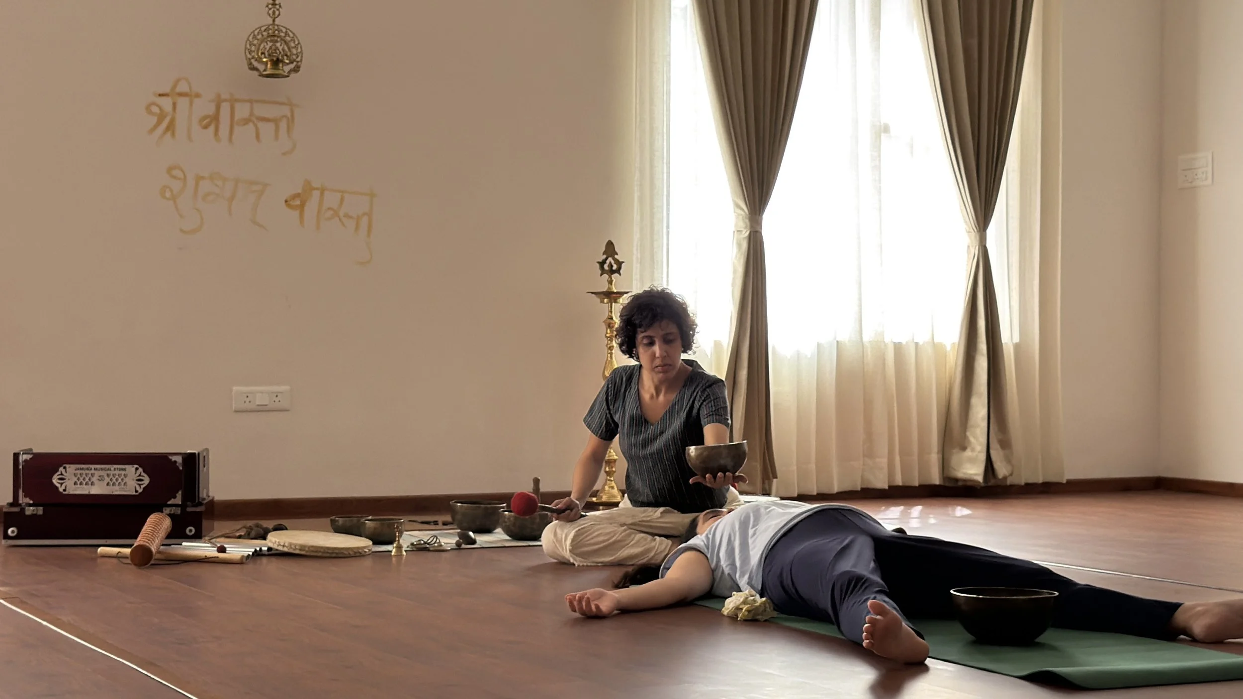 Aarti Babhoota leading a sound session as a participant rests on the floor