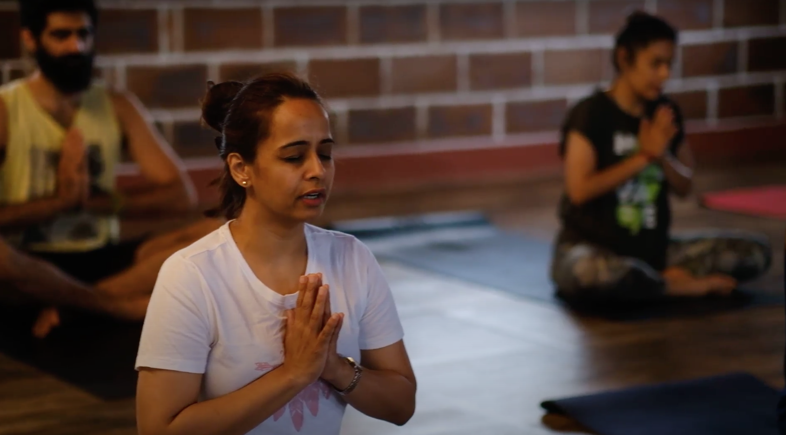A participant in meditation with palms joined at a Yukah programme in Mysore.