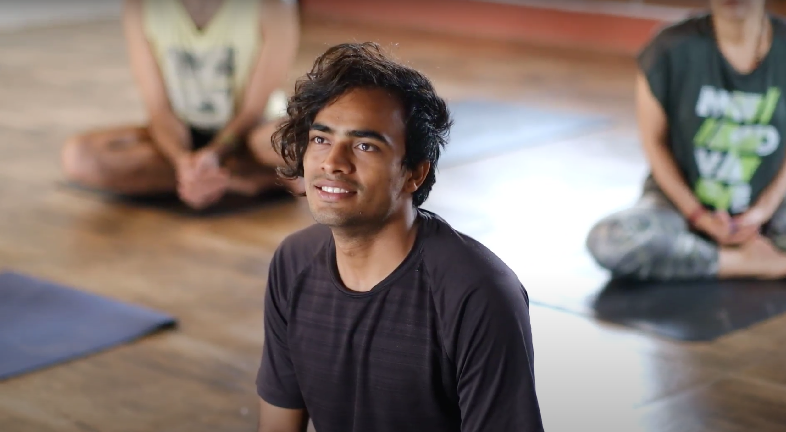 A smiling participant during a small group yoga class at a Yukah programme.