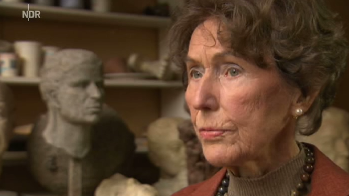 Ältere Frau vor Skulpturen in einem Atelier oder Museum