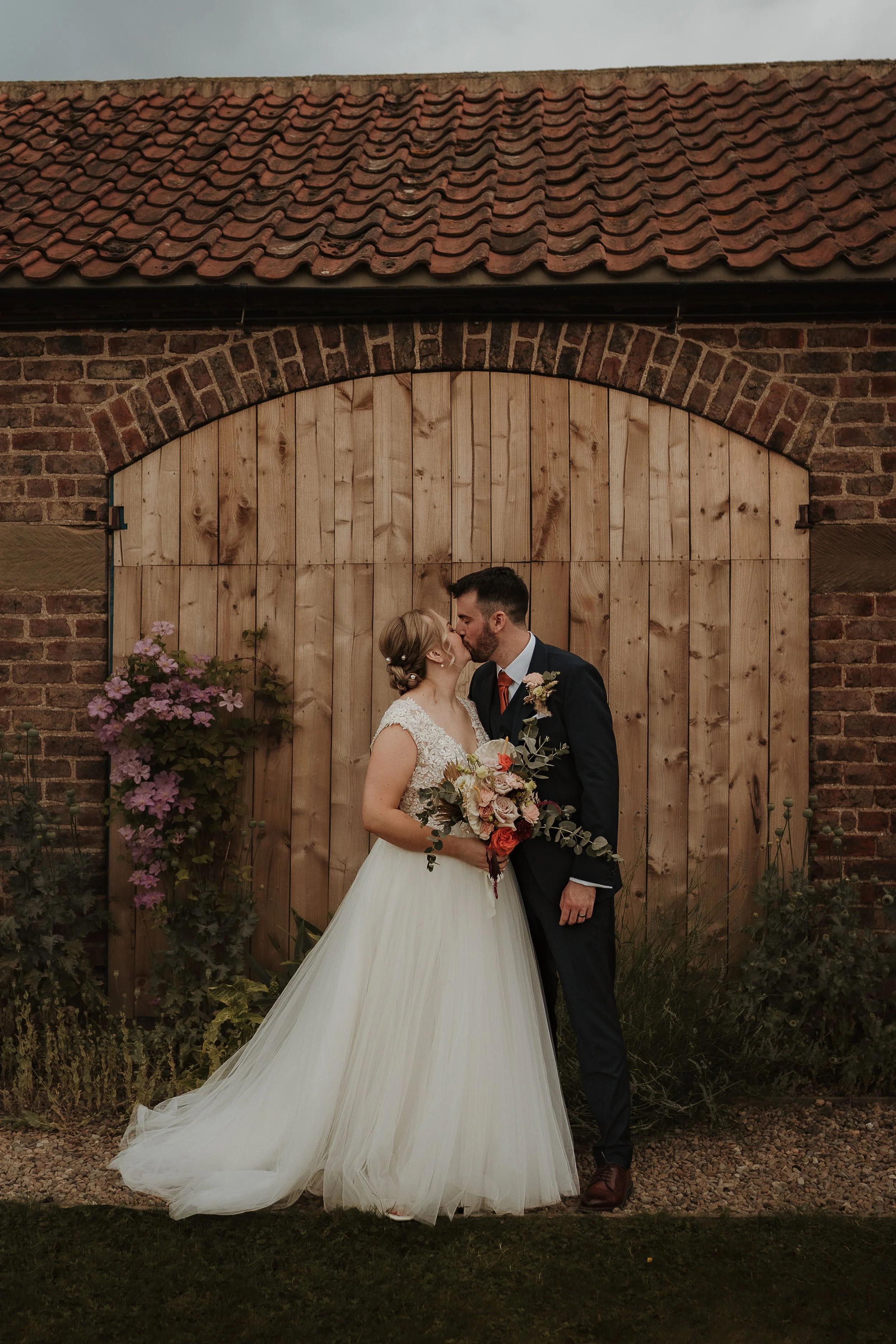 bride and groom kissing in front of barn doors