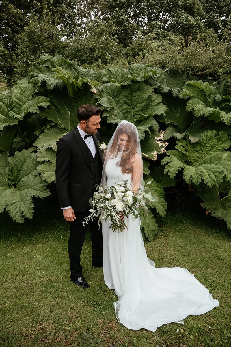 bride and groom stood outside in front of trees