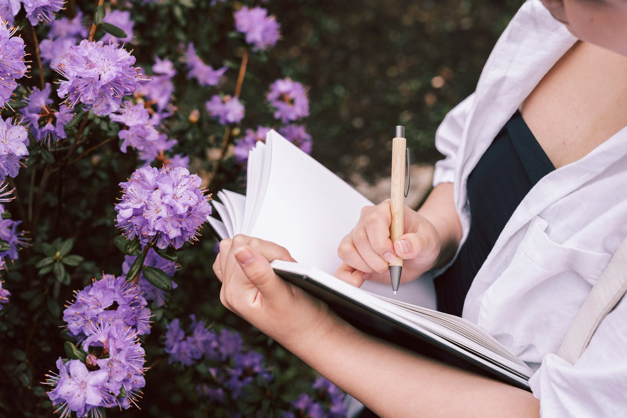 A photograph of a woman journaling near flowers to illustrate how integration is a crucial part of an IFS-informed EMDR trauma therapy intensive.