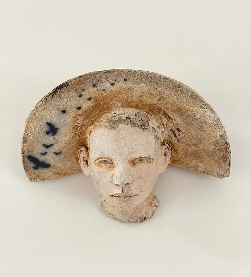"Thoughts & Memories, No. 8", ©HG. Wall-mounted ceramic sculpture head with hat, mid-fire red sculptural clay with engobe, oxide, and underglaze.