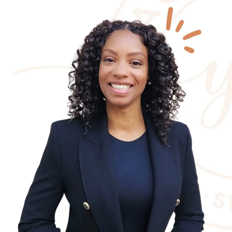 A woman with curly black hair and a bright smile, wearing a black blazer over a black top, standing against a white background with light decorative elements.