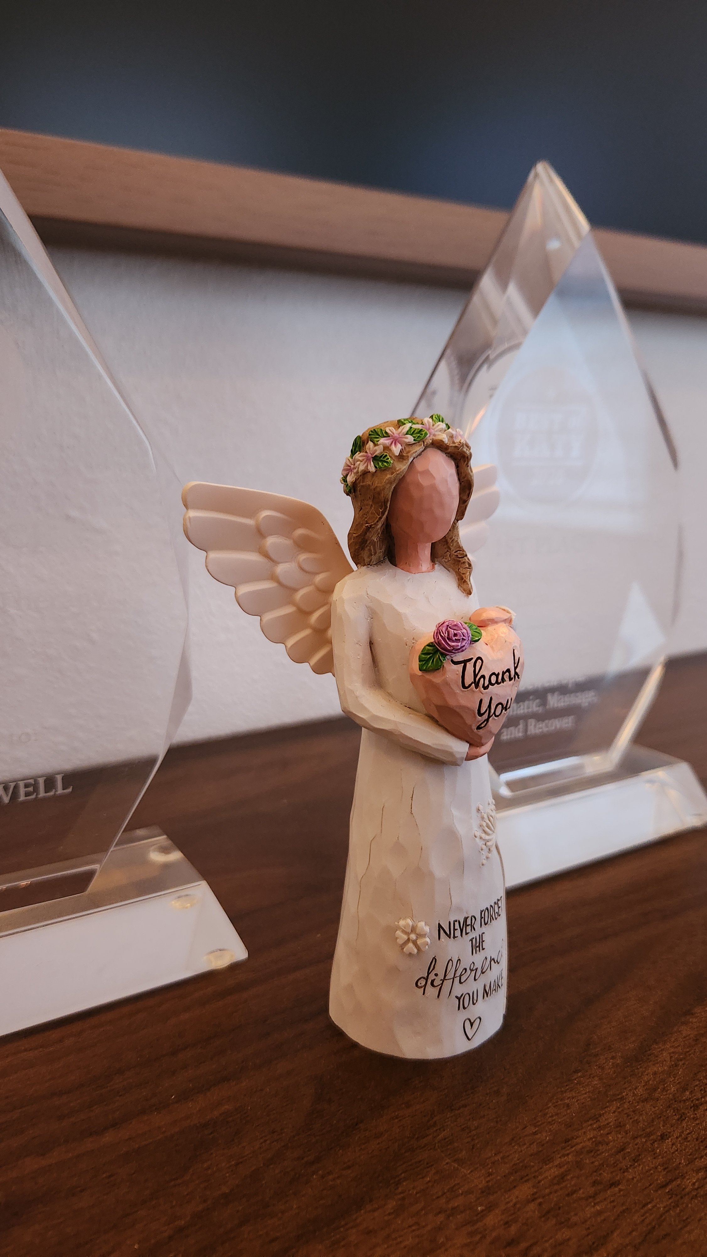 A glass award trophy on a wooden shelf against a green wall, with a red stamp graphic on the left that reads "Best of Katy 1st Place" for 2025.
